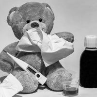 Teddybär mit Fieberthermometer, Taschentüchern und Medizin