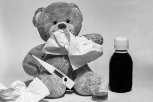 Teddybär mit Fieberthermometer, Taschentüchern und Medizin